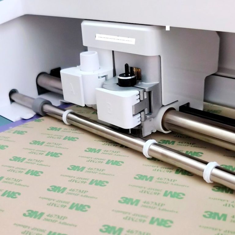 corte de materiales Cortadora de vinilo en acción, sobre una hoja de material etiquetado.